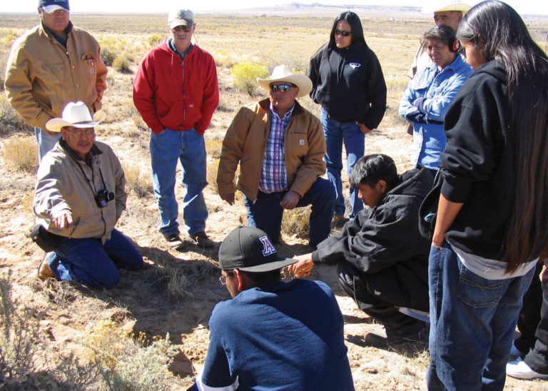 A group of ranchers in a field discussing something A group of ranchers in a field discussing something