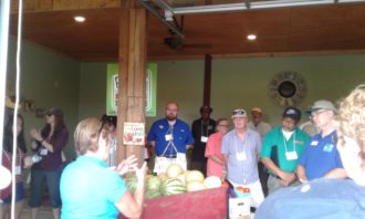 Delvin Farms People gathered around at Delvin Farms listening to a woman talk at the front of a barn
