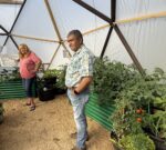 Trainees stand in dome with vegetables and flowers
