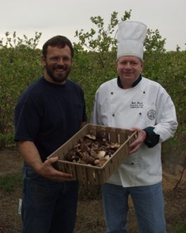 A man handing over a crate of harvest to a chef