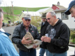 People gathered looking a sample of soil in a bin