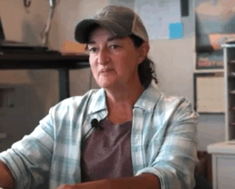 Woman sitting in an office, wearing a ballcap