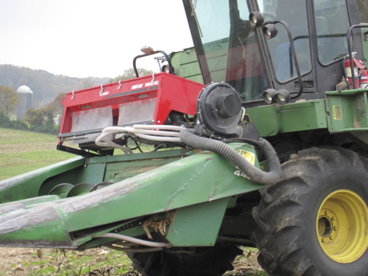 an air seeder box and tubes mounted on the front of a combine