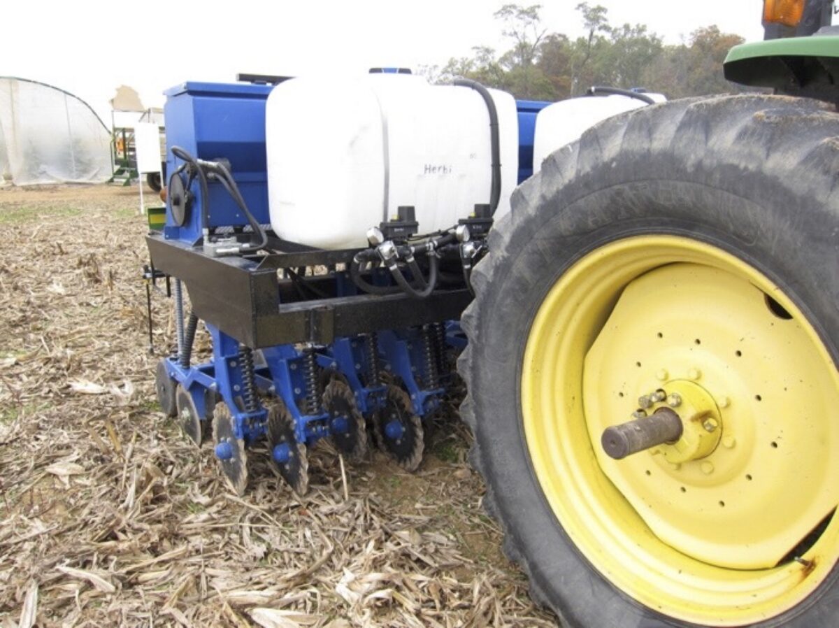 a side view of the high clearance drill mounted onto a tractor