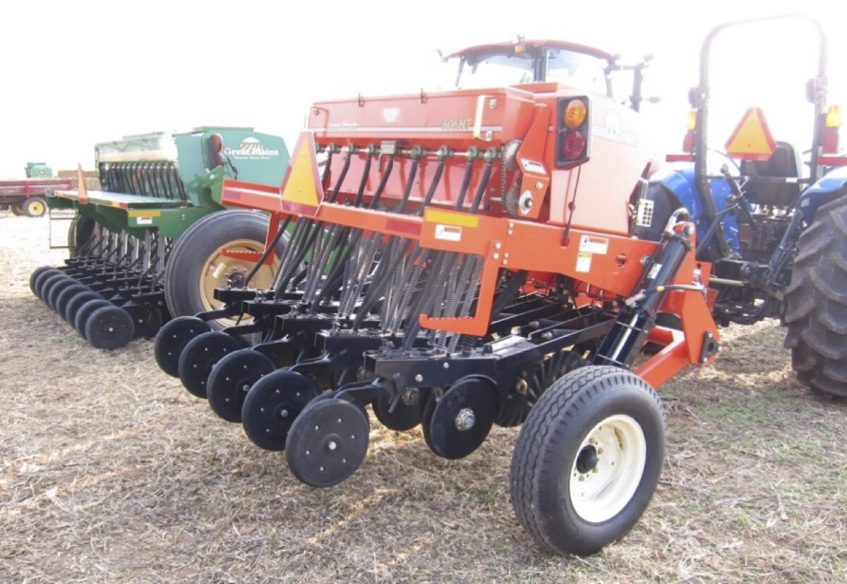 Two grain drills made by different companies are side by side in a lot