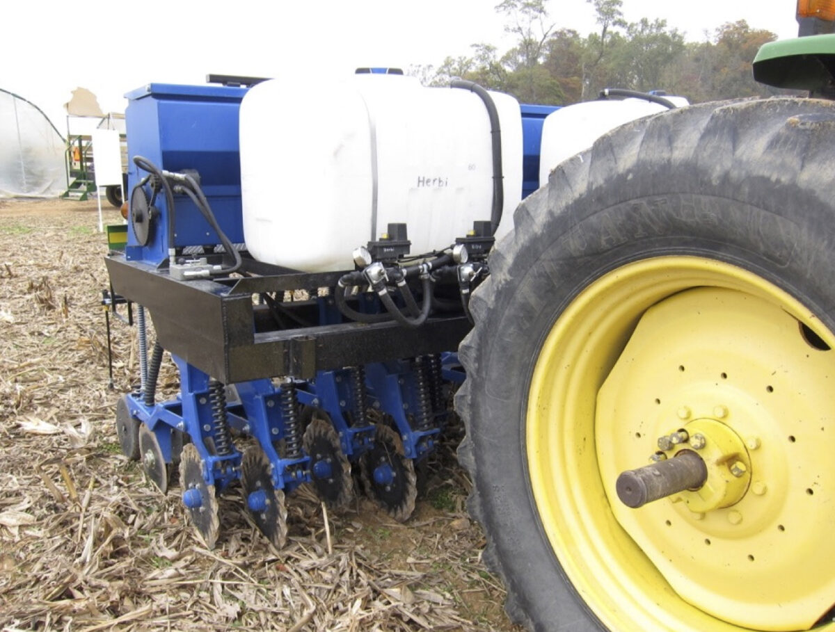 a side view of the high clearance drill mounted onto a tractor