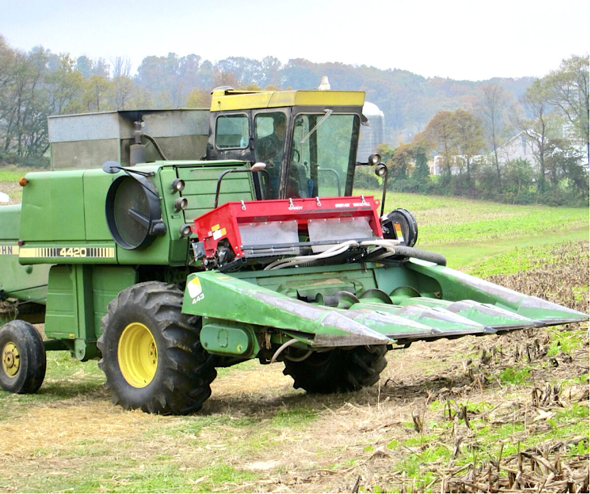A combine that has been modified to include an air seeder is being driven in a field