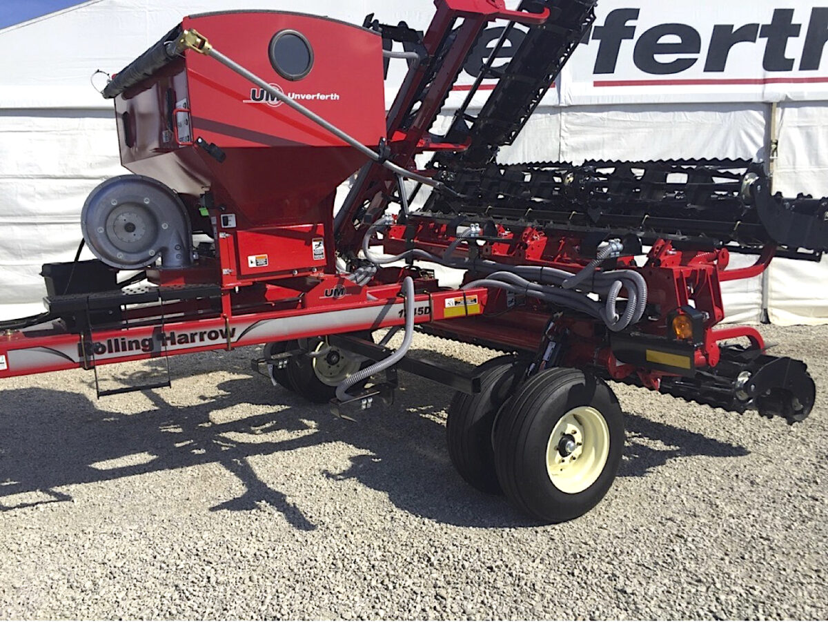 A rolling harrow with a cover crop air seeder at a dealership or trade show
