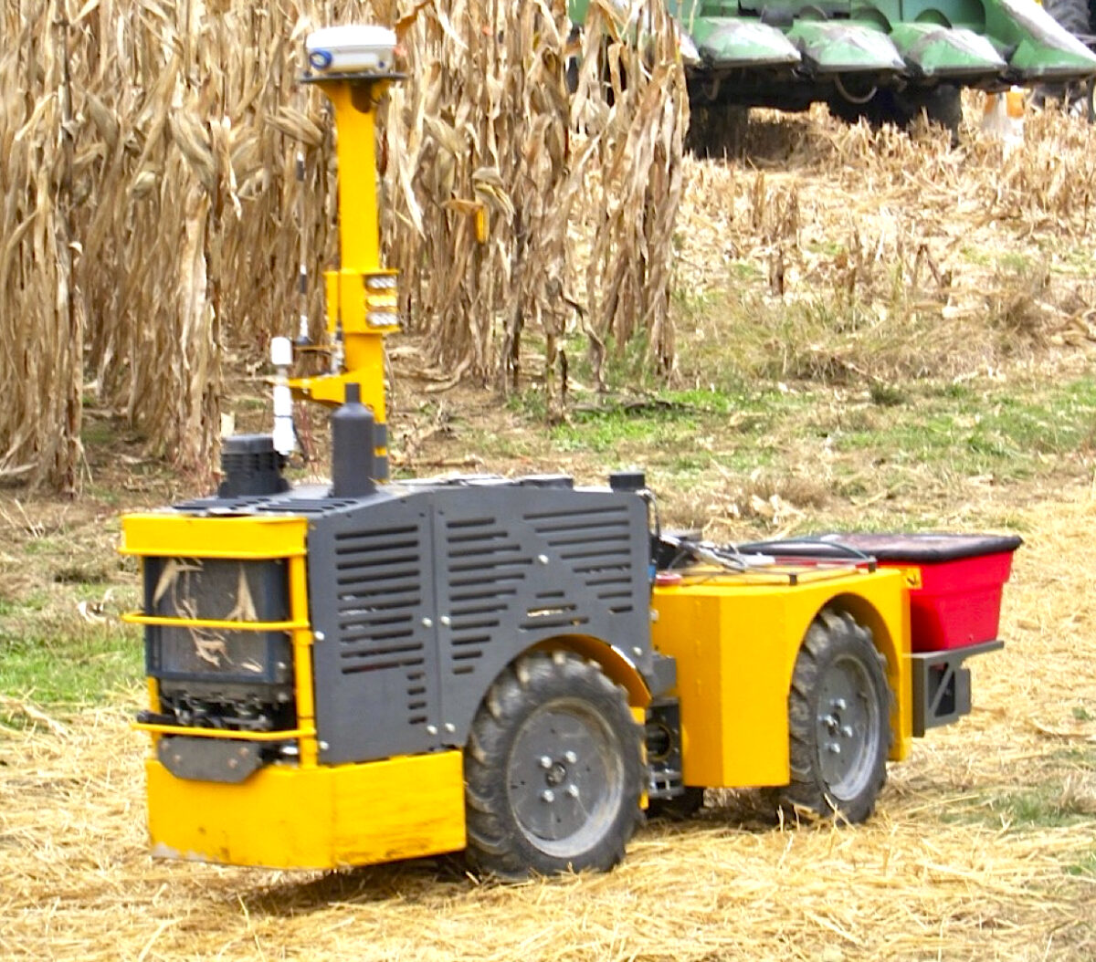 A prototype of a RowBot. It's a small, four-wheeled machine with a front mounted seeder box and a GPS tower on top, and it's narrow enough to travel through a row of corn.