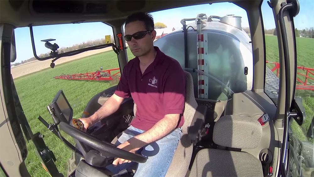 man (John burk) riding a piece of farm equipment in an open field