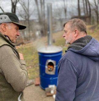 Two men talking to each other outside in front of a blue can.