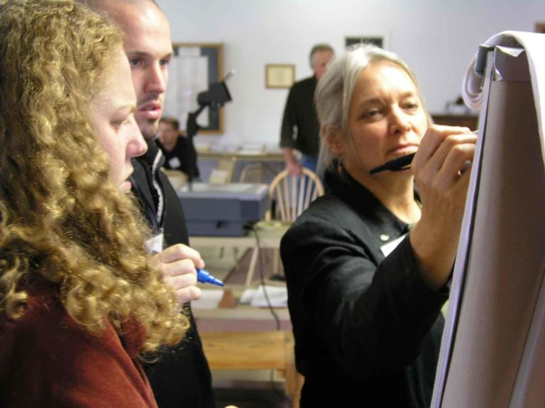 Three people talking and writing on a board Three people talking and writing on a board