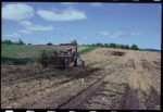 A tractor in a light brown field with grass to the left