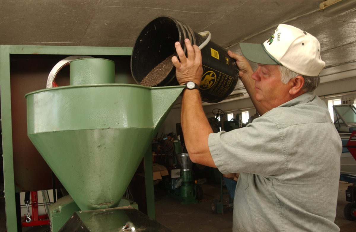Roger Rainville pouring canola seed into a press.