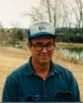 Ron Macher headshot wearing a hat and glasses and standing outside