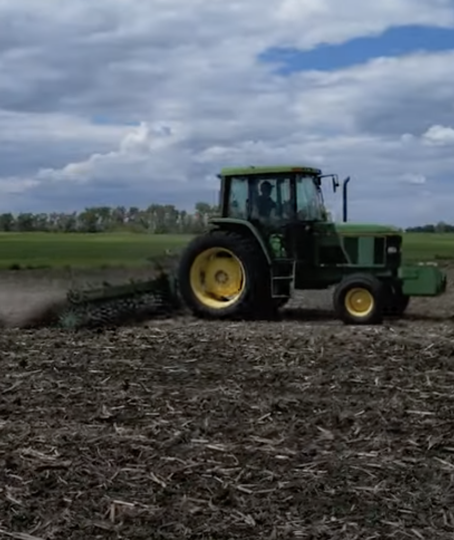 A tractor along a tan field with grass in the background