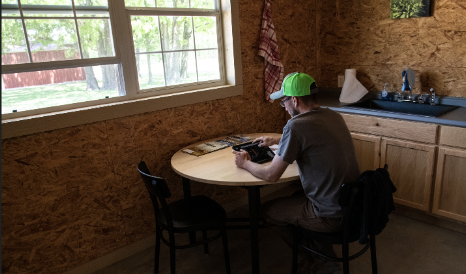 A man sitting at a wooden table looking at something on an iPad