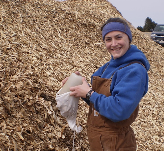 Woman standing in front of a large mount of wood chips