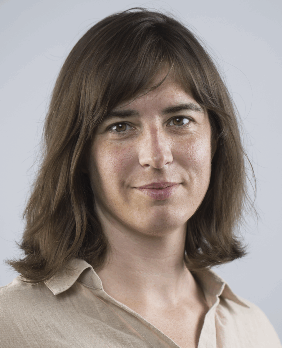 Headshot of a woman with brown hair and a tan shirt