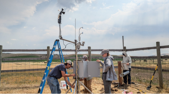People gathered around a irrigation machine in a field