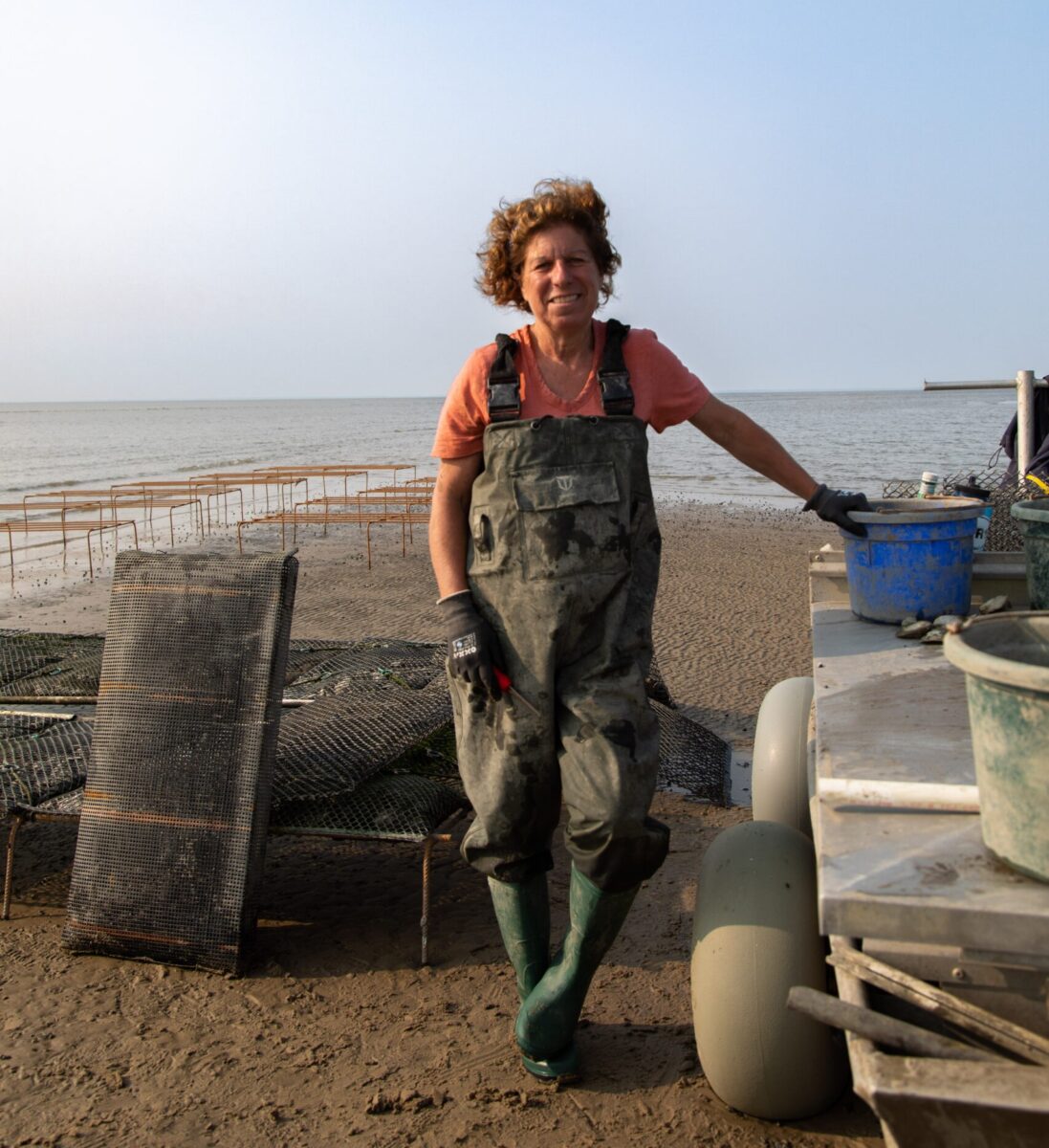 oyster farmer posing on beach with equipment