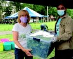 two people holding produce in a bin
