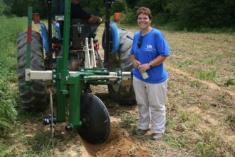 Sarah Fannin standing next to a sweet potato harvester.