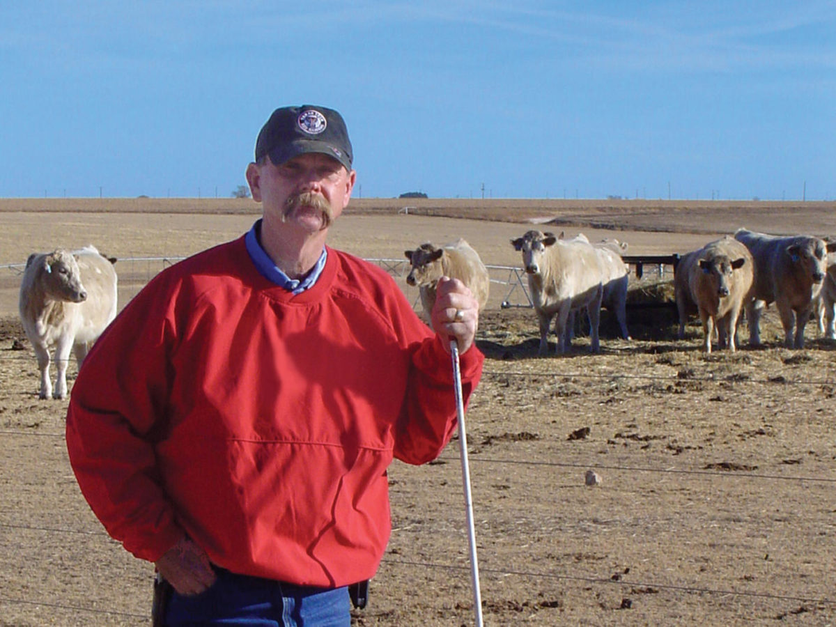 Man with cattle in the background in a dry area