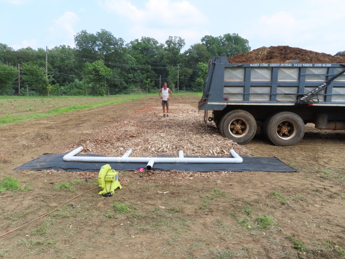 A man standing behind a truck filled with compost