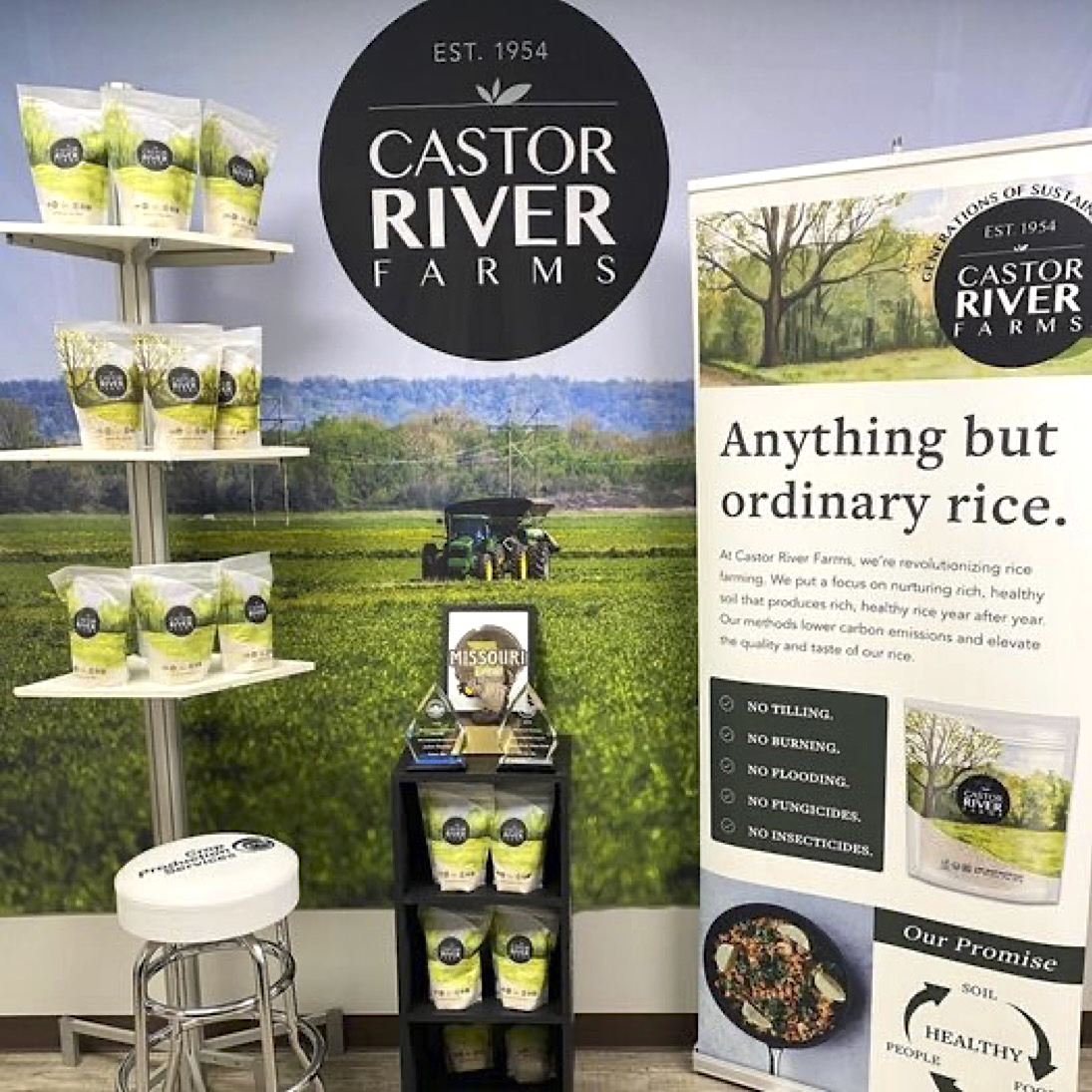 This display has a backdrop with a photo of the farm, an informational banner and a few shelves with products on them.