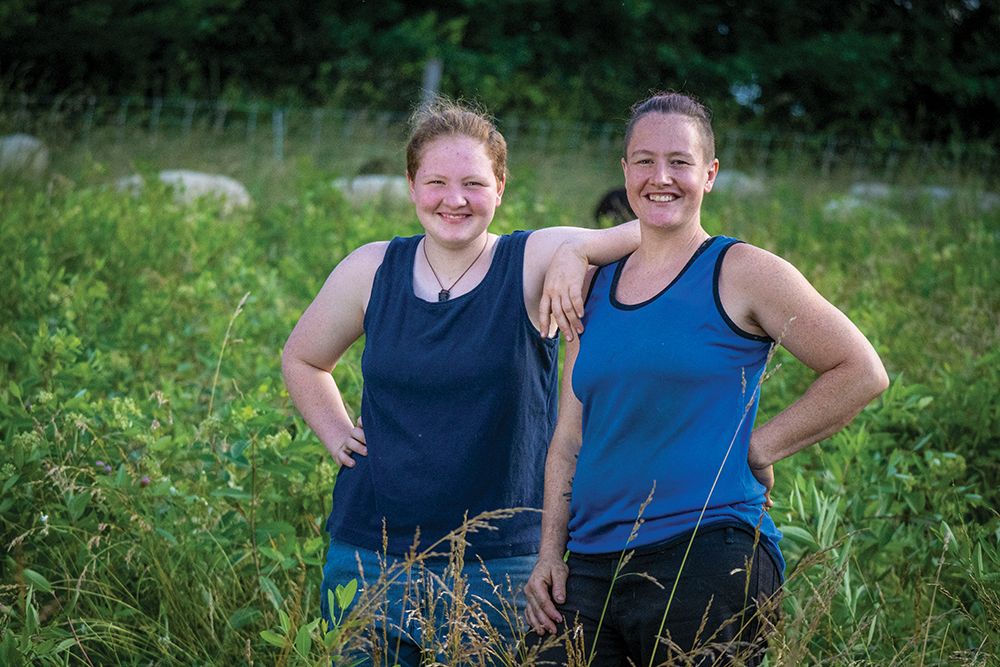 two women standing in a sheep pasture