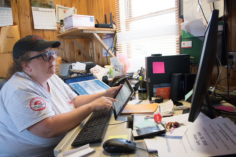 A woman at her office computer is processing invoices