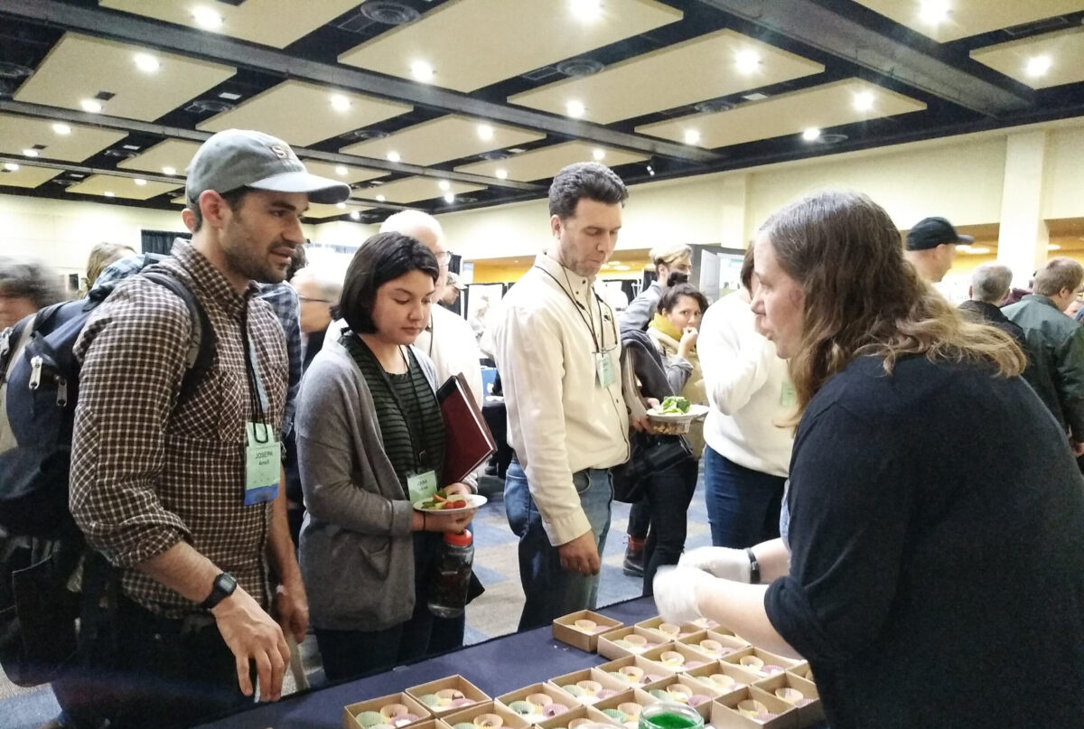 A woman talking to people at a conference to give them free samples