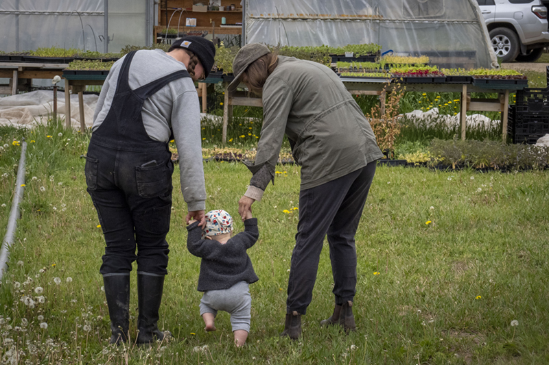 Two women walk with their baby at their farm