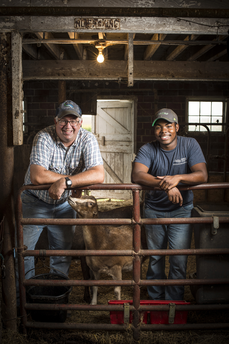 A farmer mentor posing with the college student who works at his farm