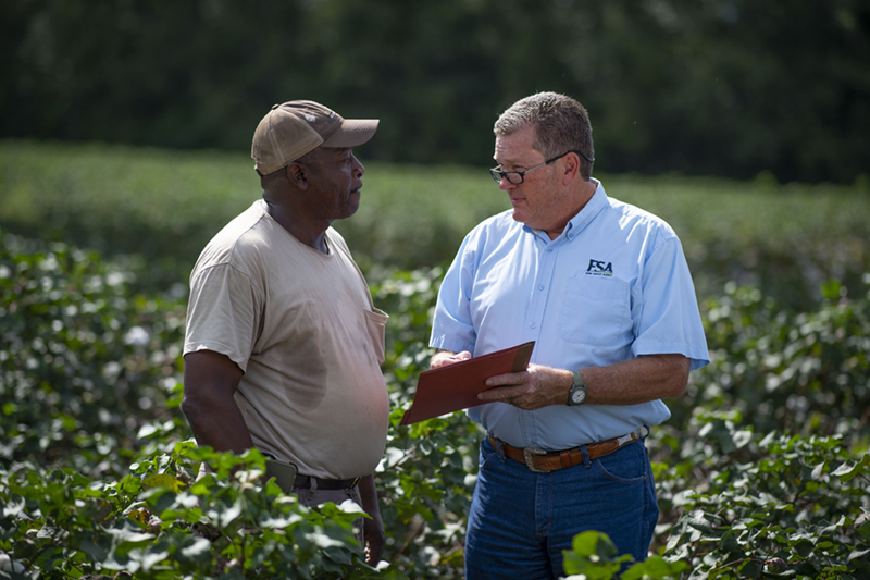 A farmer is in his field talking with a USDA FSA agent