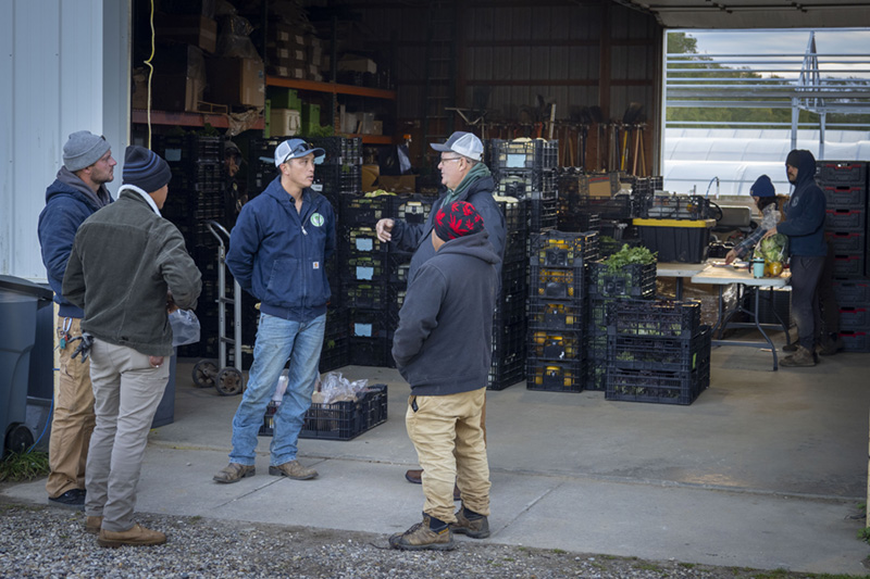 A farmer talks to his crew outside a produce packing shed