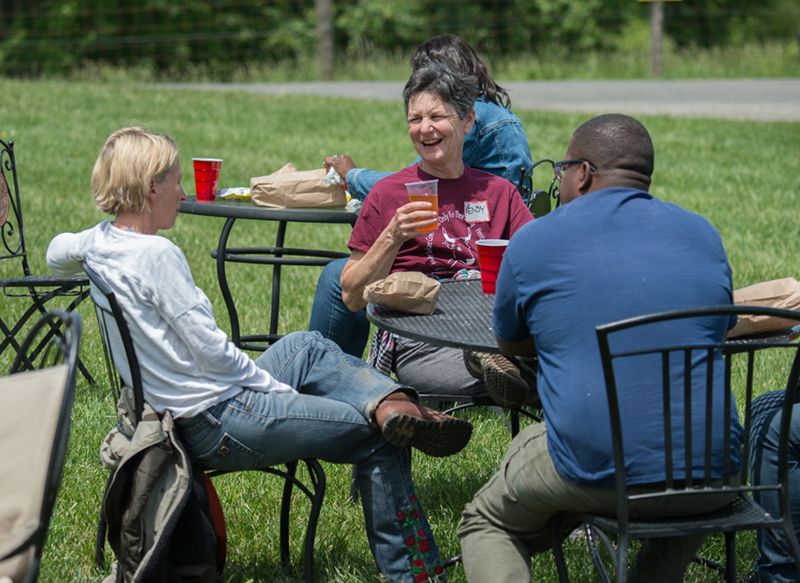 Three farmers are talking and having lunch outdoors at a workshop