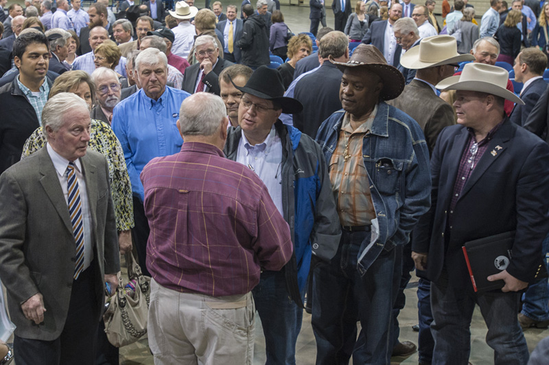 A group of farmers talk with a USDA leader after a talk at a conference