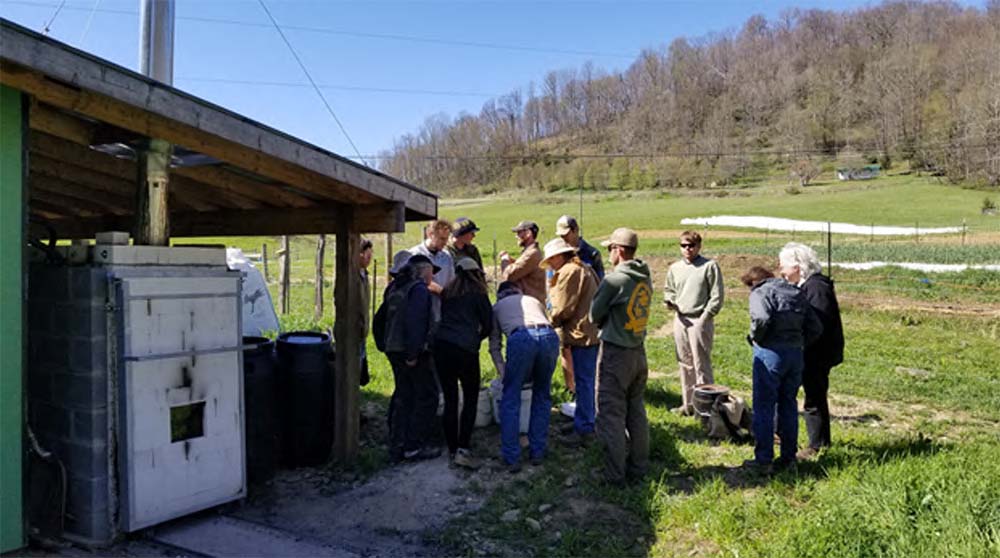 Farmers look at a biochar kilm