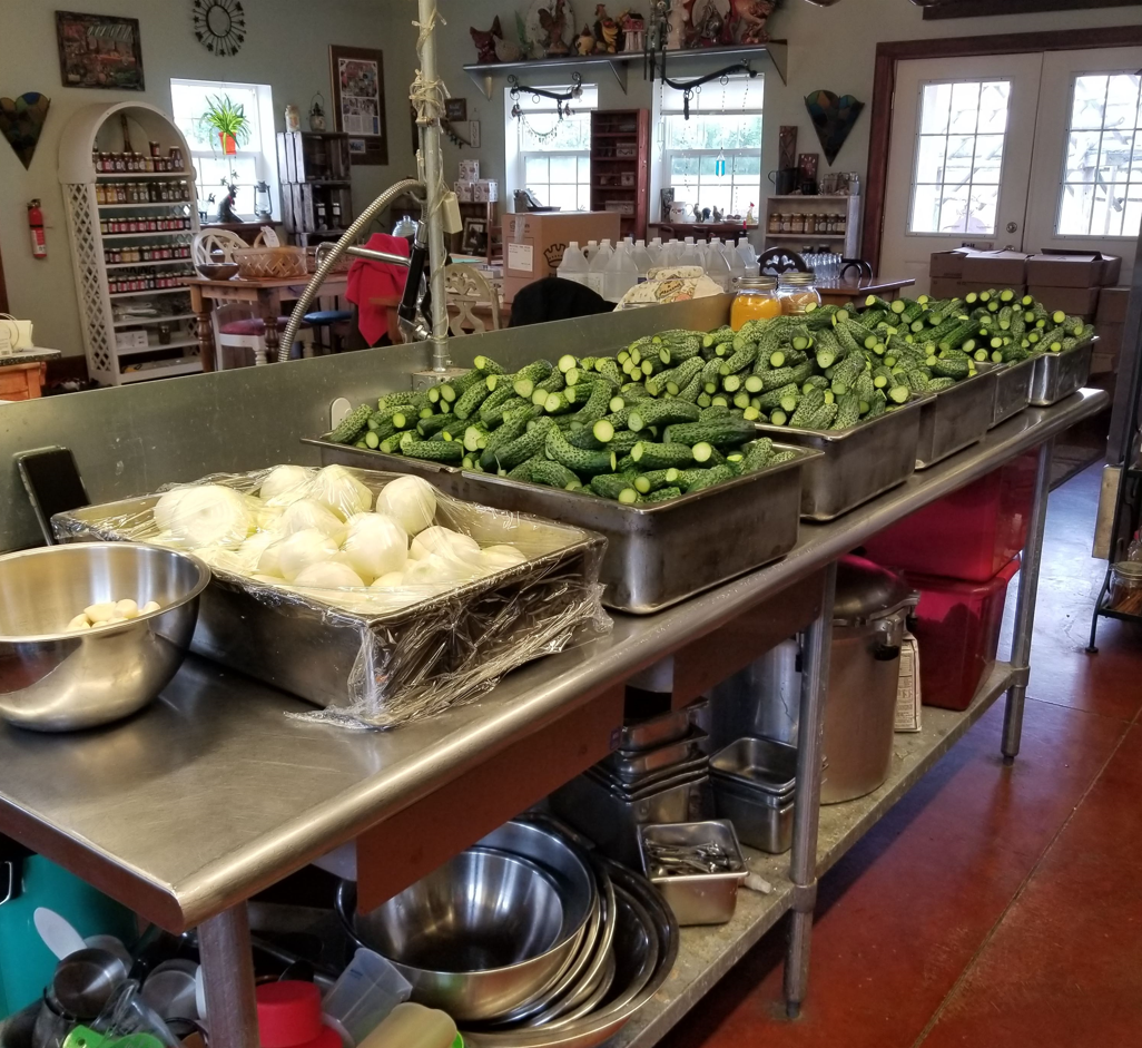 multiple containers of cucumbers and onions in a kitchen 