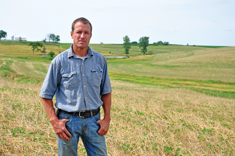 A farmer standing in a hay field.