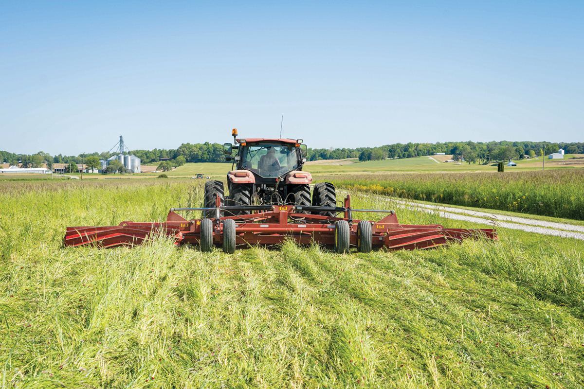 A large tractor mounted roller crimper in a field.