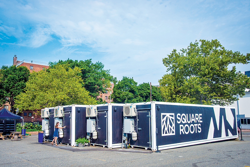 Container farms on pavement roads in front of a field being used as farms
