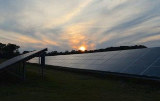 A solar panel field with a rising sun in the distance