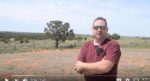 Video Screenshot of a man talking in a dry field