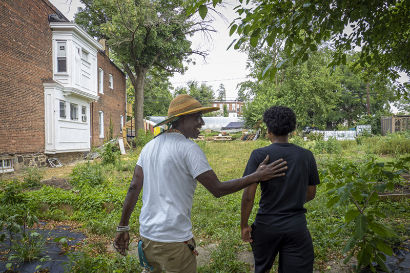 An urban farmer walks with a teenage boy who works at the farm with him