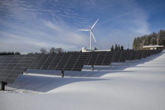Wind Turbine behind rows of solar panels
