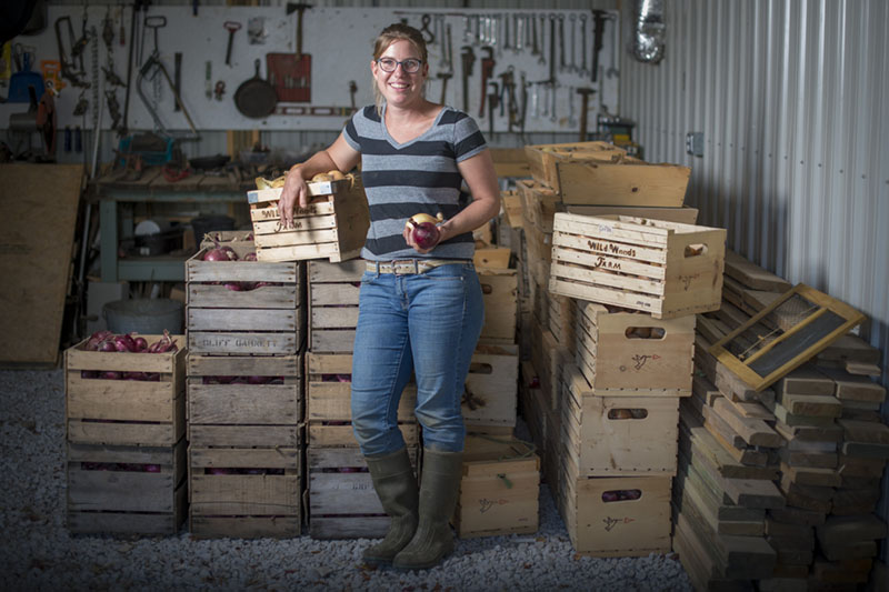 A young white woman posing in a toolshed with crates of apples